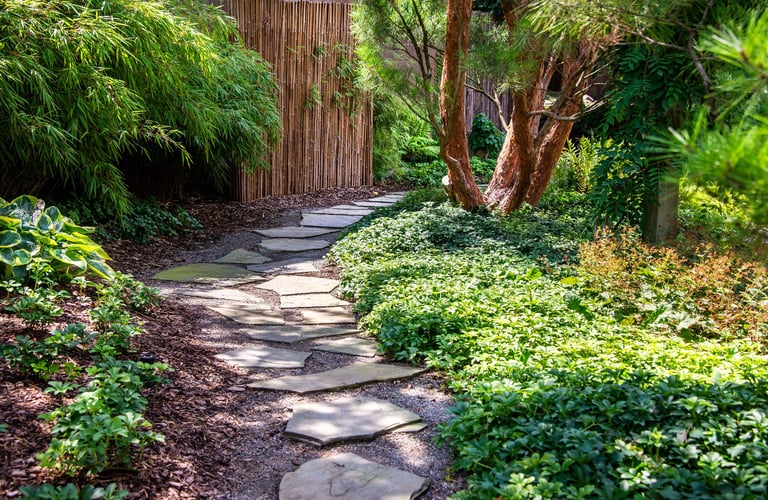 A winding stone path leads through the lush, green Japanese garden